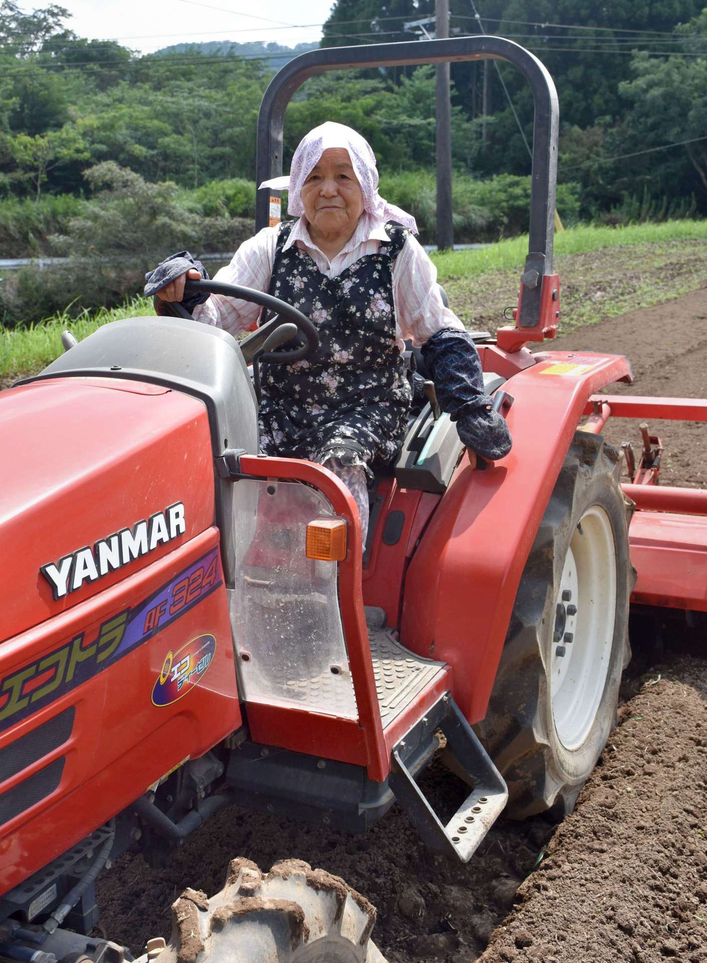 畑でトラクターを運転する年神ミエ子さん＝曽於市財部