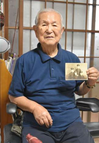 海軍甲種飛行予科練習生時代の写真を手に当時を振り返る児玉宗孝さん＝伊佐市大口針持