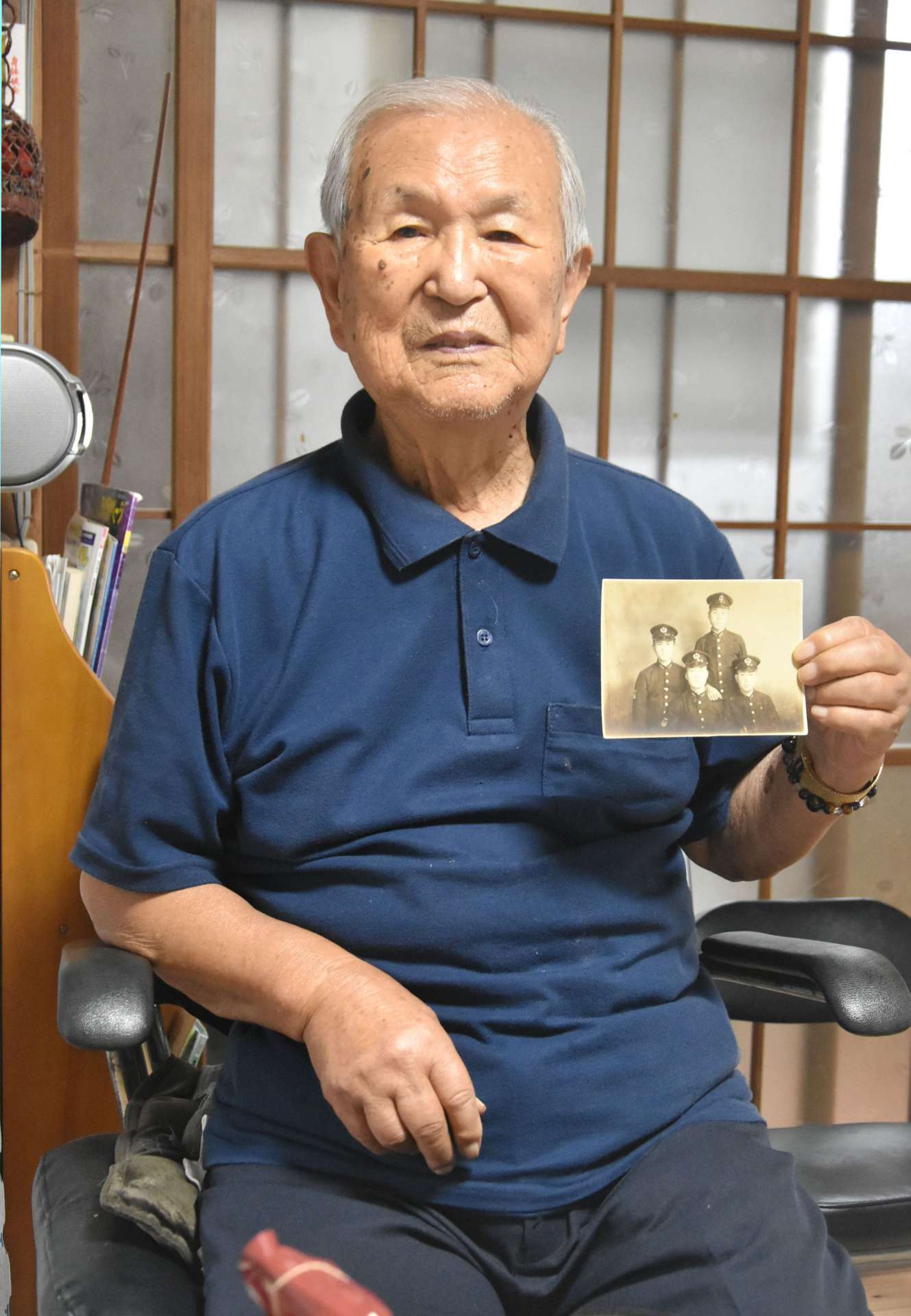 海軍甲種飛行予科練習生時代の写真を手に当時を振り返る児玉宗孝さん＝伊佐市大口針持
