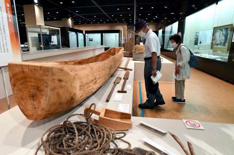 スブネ（丸木船）や漁具などの展示物に見入る来場者＝１日、鹿児島市の黎明館