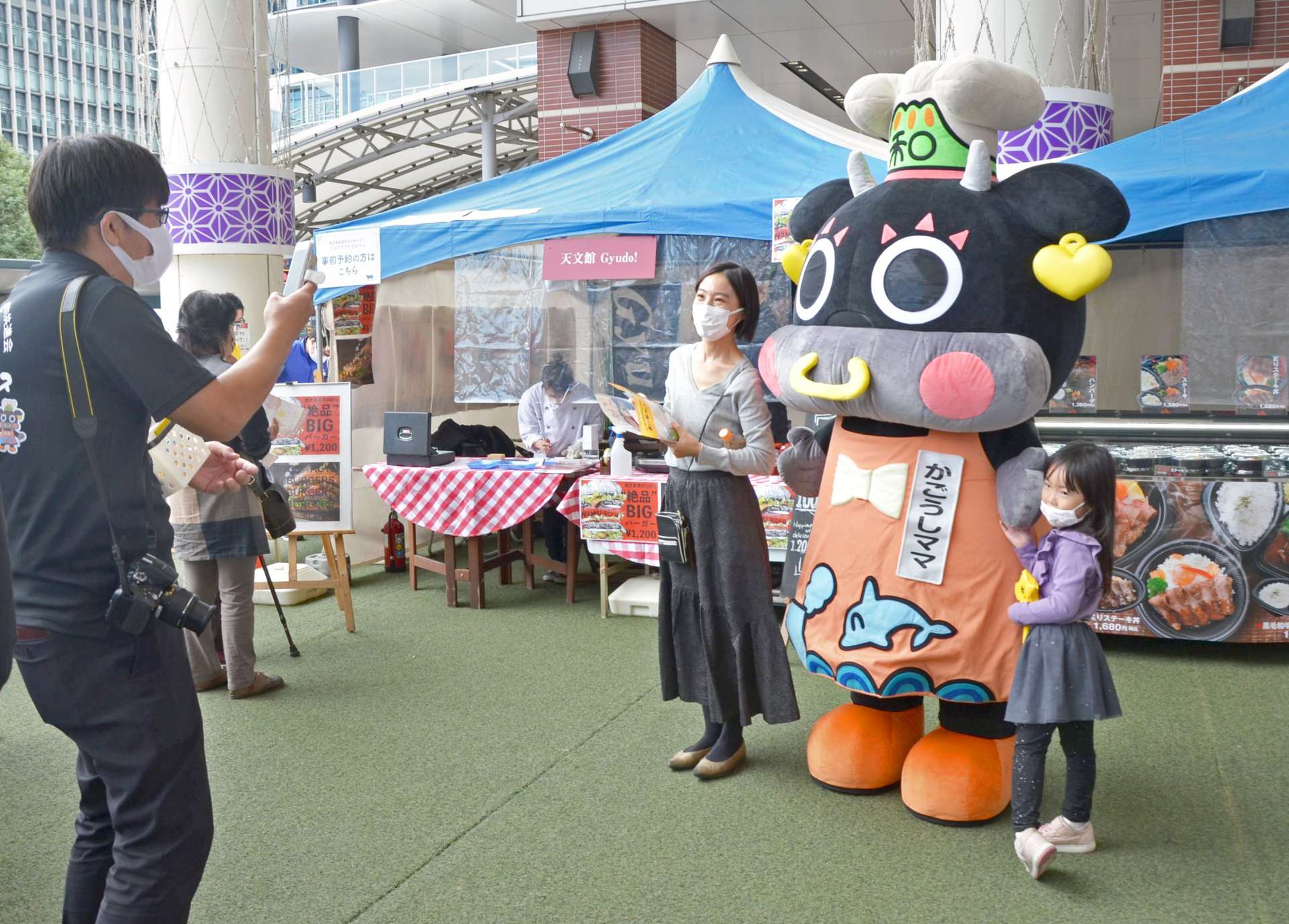 「かごうしママ」との記念撮影を楽しむ親子＝２３日、鹿児島市のアミュ広場