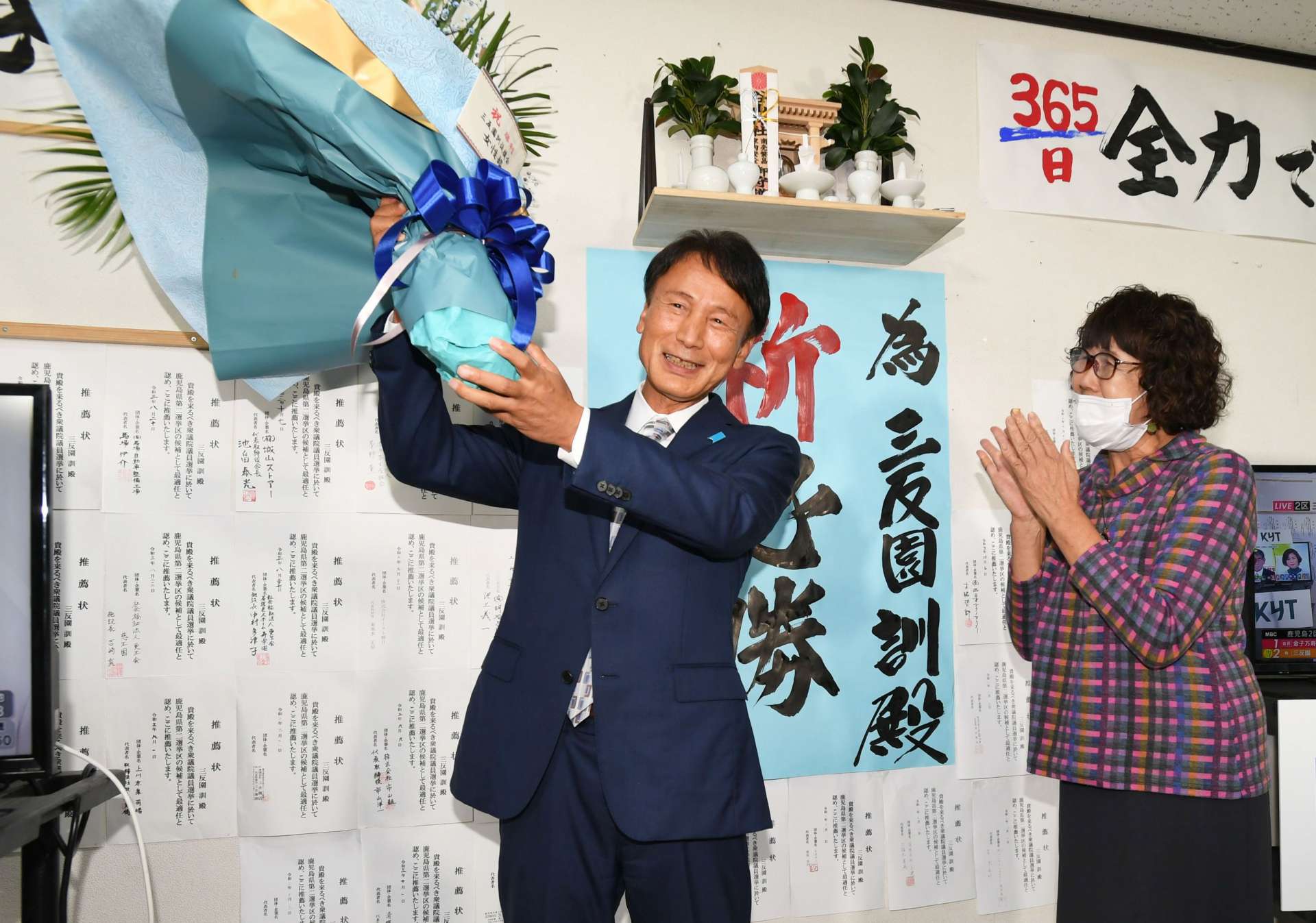 支持者からの花束を手に喜ぶ三反園訓さん＝３１日午後１０時５２分、鹿児島市谷山中央３丁目