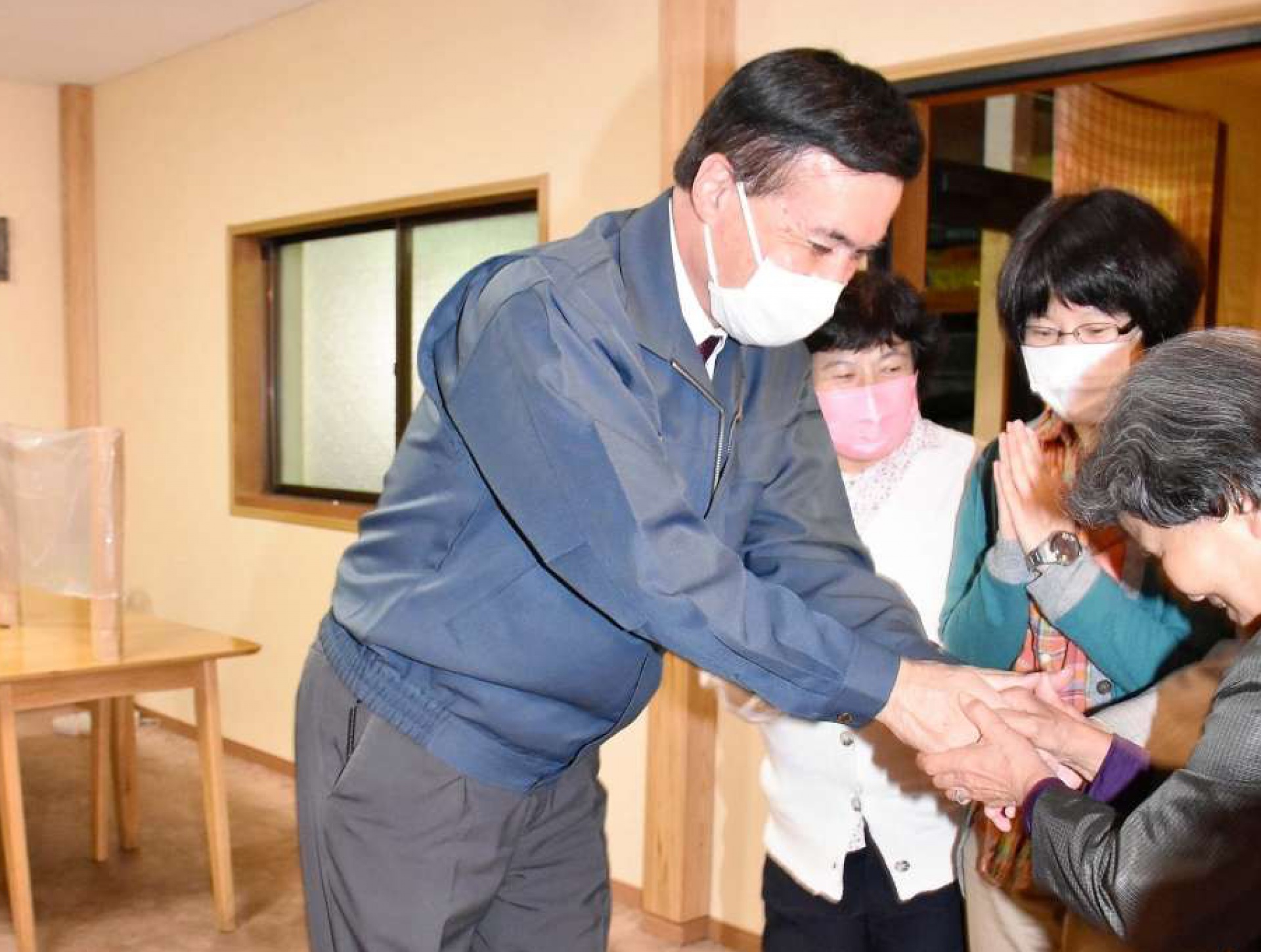 比例で復活当選し、支持者と握手を交わして喜ぶ小里泰弘さん＝１日午前１時１０分ごろ、姶良市西餅田