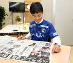 一夜明け、当選を伝える新聞に目を通す宮路拓馬さん＝１日、鹿児島市上之園町