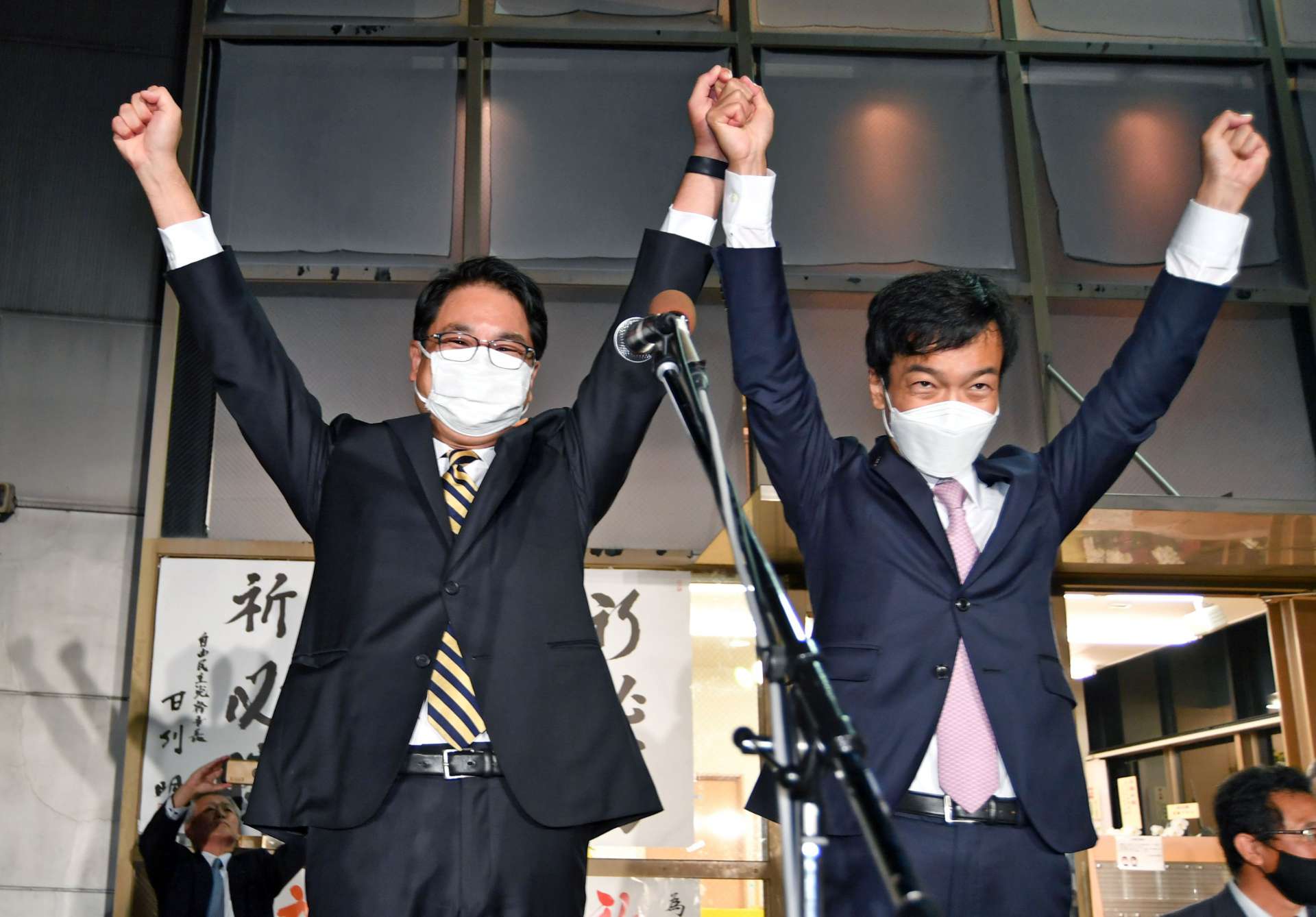 当選後、手を取り合って拳を突き上げる宮路拓馬氏（右）と保岡宏武氏＝１日、鹿児島市上之園町