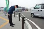 つじ立ちし、頭を下げる小里泰弘氏＝１日、薩摩川内市の国道３号