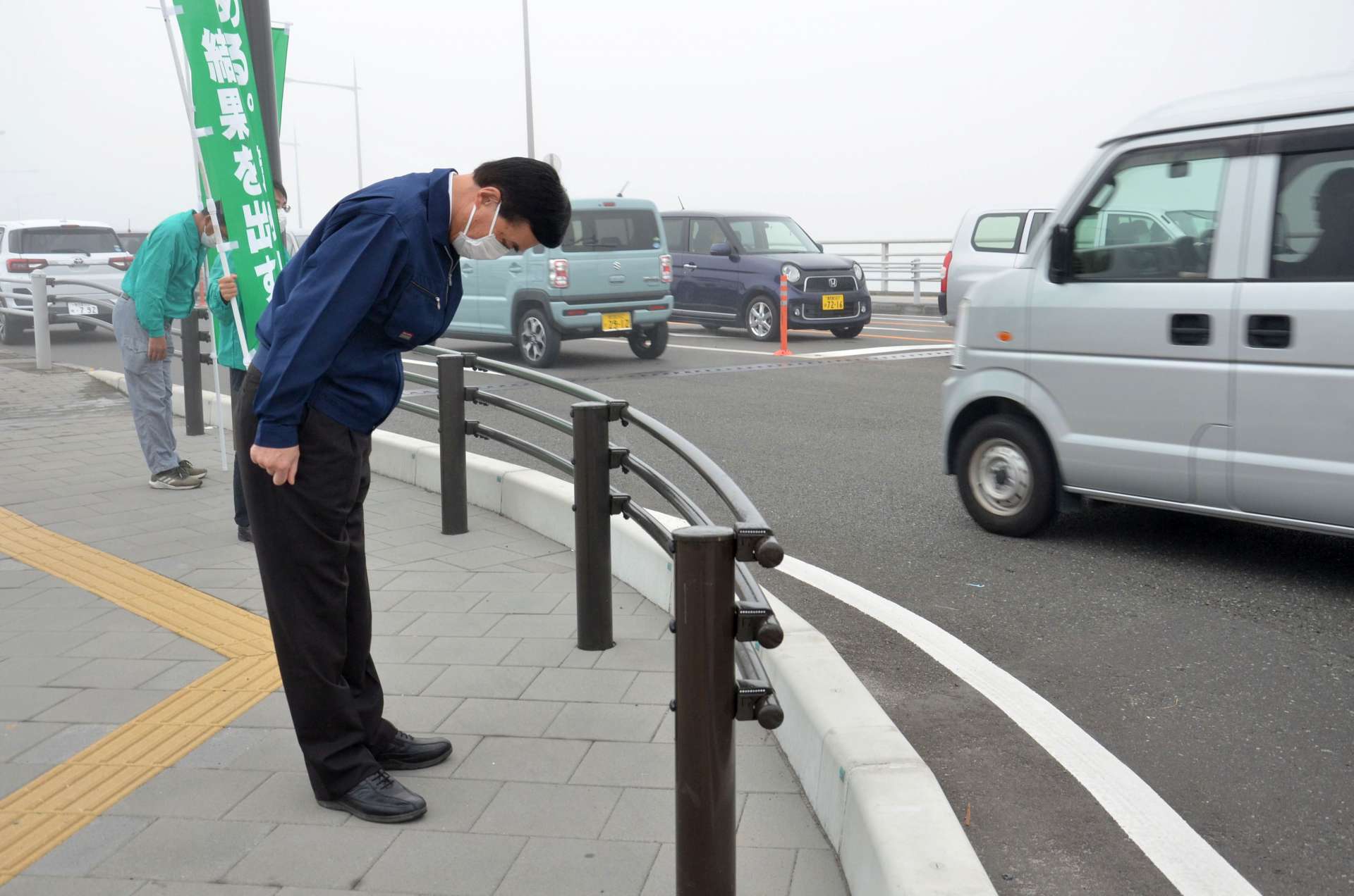 つじ立ちし、頭を下げる小里泰弘氏＝１日、薩摩川内市の国道３号