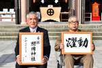 照国神社に奉納した文字を持つ昭和書体の綱紀栄泉さん（右）と坂口茂樹会長＝鹿児島市の照国神社