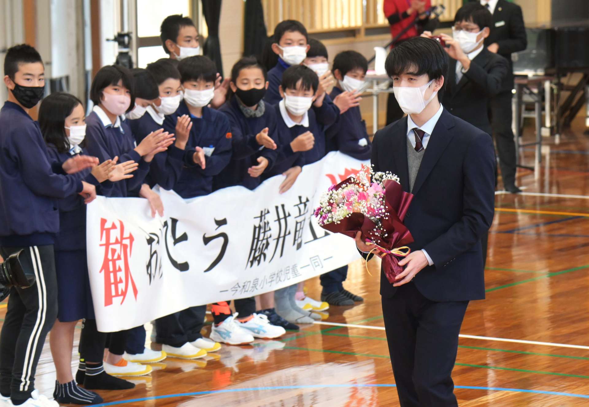 児童らに拍手で見送られる藤井聡太竜王＝３日、指宿市の今和泉小学校
