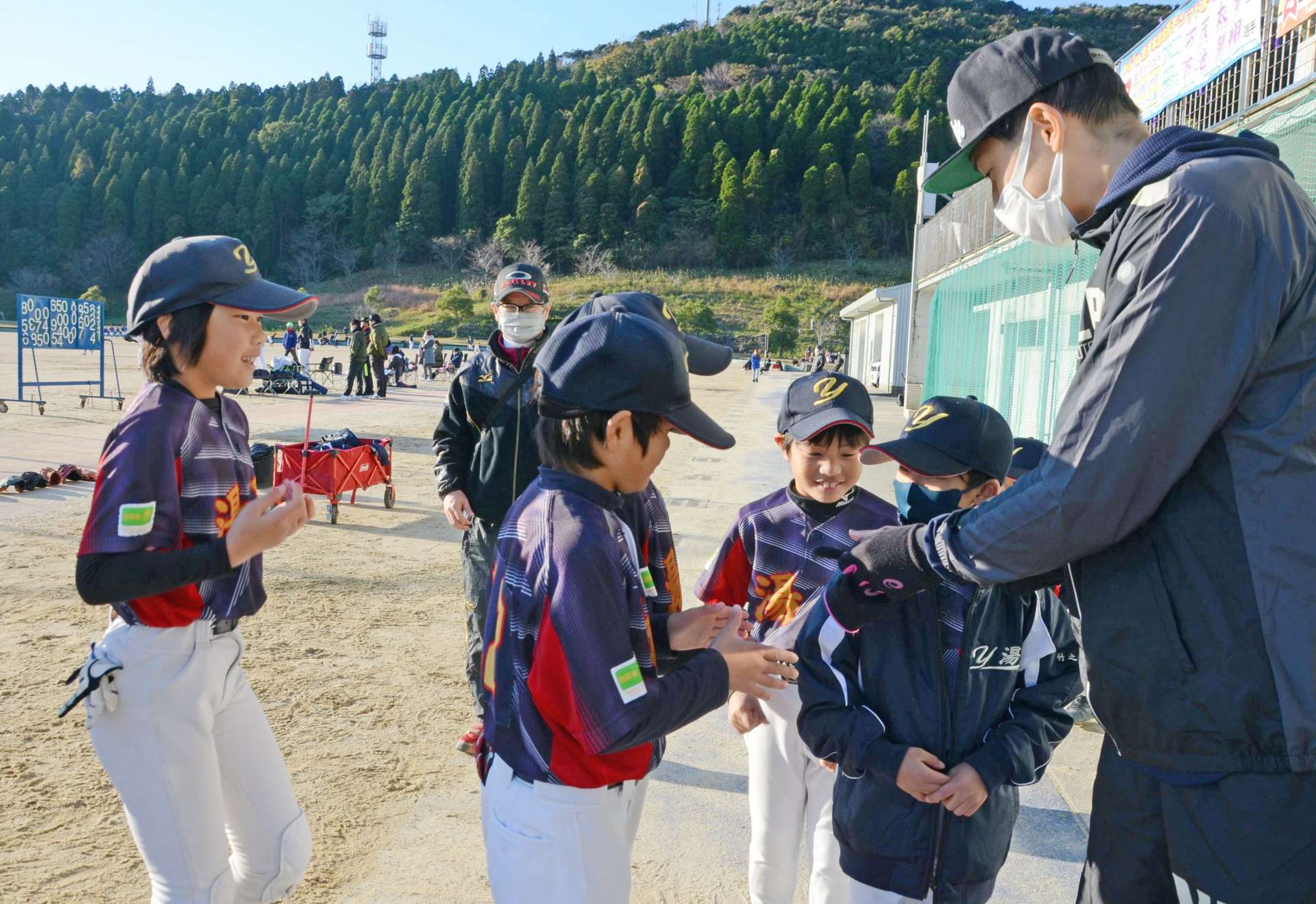 子どもたちと握手して交流する横田慎太郎さん＝日置市東市来総合運動公園