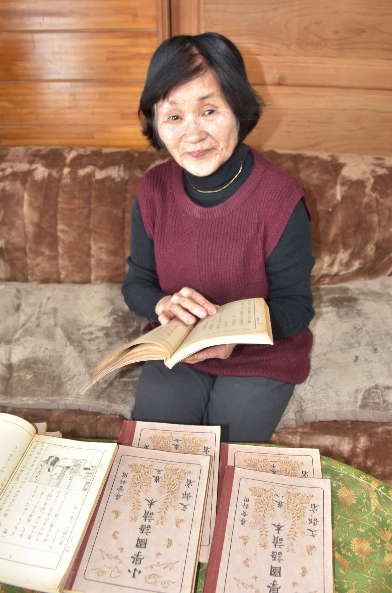戦前の教科書の復刻版を手に、当時を思い出す井上悦子さん＝阿久根市脇本