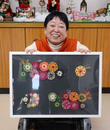 「チェルシー」のパッケージをイメージした編み物作品を手にする川路ちづ子さん＝日置市伊集院の太陽の里療護園