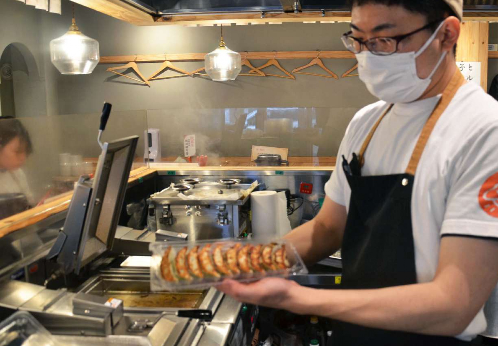 焼き上げたギョーザを持ち帰り用に手早く詰める店員＝鹿児島市武１丁目