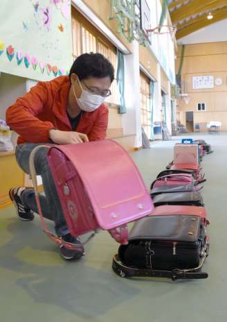 集まったランドセルを並べる保護者＝霧島市国分福島１丁目の天降川小学校