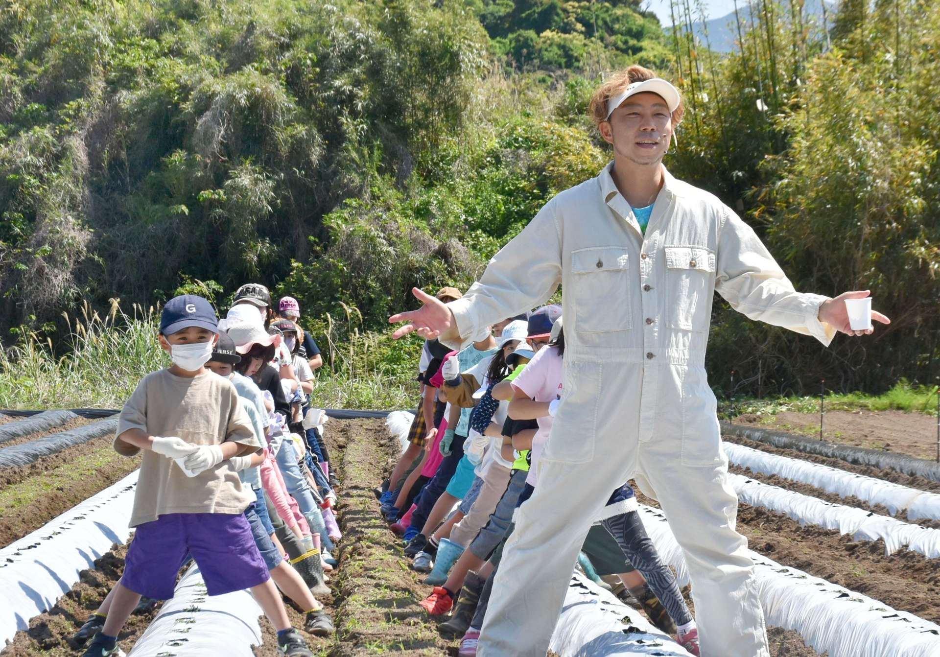 踊りながら枝豆の種を植えるＵＳＡさんと子どもたち＝１６日、南大隅町根占川北