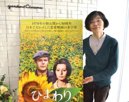 ウクライナ支援寄付上映中の「ひまわり」ポスターと黒岩美智子支配人＝鹿児島市呉服町のガーデンズシネマ