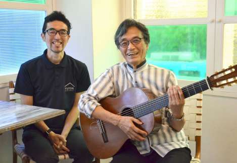 弾き語りをする川野恭司さん（右）と、ユーチューブの出演を依頼した上野康弘さん＝鹿児島市名山町