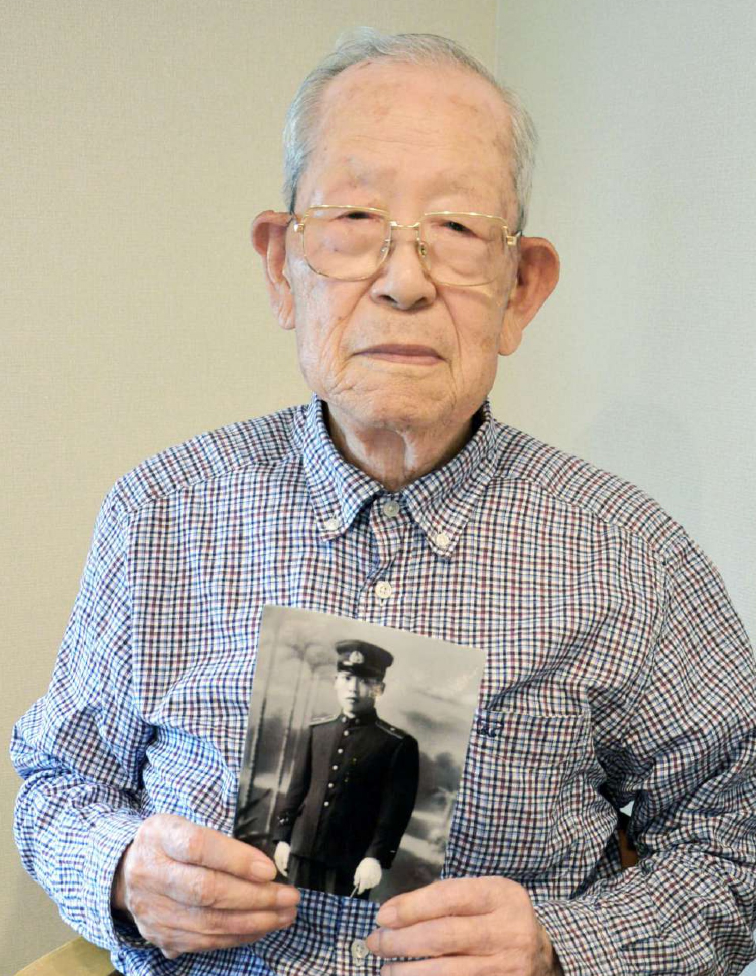 税関職員時代の写真を持つ渕上留男さん＝さつま町轟町