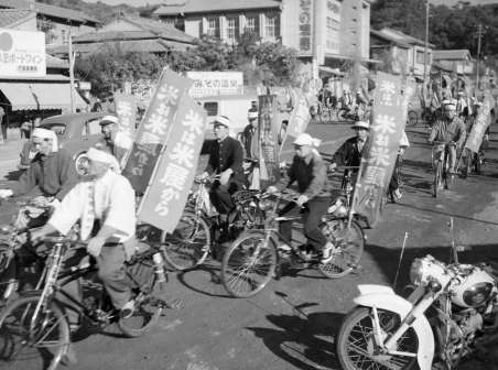 「ヤミ米追放して配給米を」と訴えて鹿児島市内（清水町付近）を自転車、オートバイなどでパレードする米屋さん＝１９５９年１２月