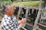 スマートフォンを使って給餌機を操作する増田好人さん＝佐賀県鹿島市