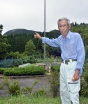 上床山の方角を指し、戦時下の様子を振り返る折橋義行さん＝阿久根市山下