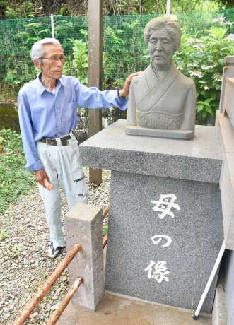 庭に飾る実母の銅像を見ると、戦争時代を思い出すという折橋義行さん＝６月２３日、阿久根市山下