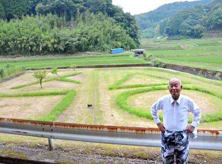 果樹園跡に広がる雑草アートと制作した窪田弘文さん＝鹿児島市花尾町