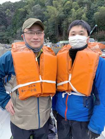 漁船に乗り込み、獅子島へ恐竜化石調査に向かう筆者（左）と中島保寿さん＝２０２１年１１月