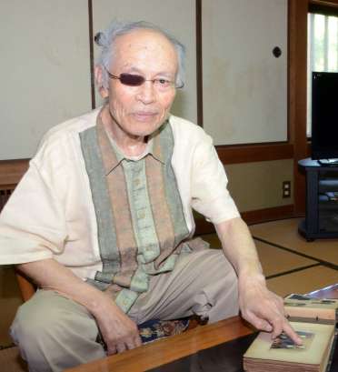 きょうだい４人で写った写真を指さす入来院元彦さん
