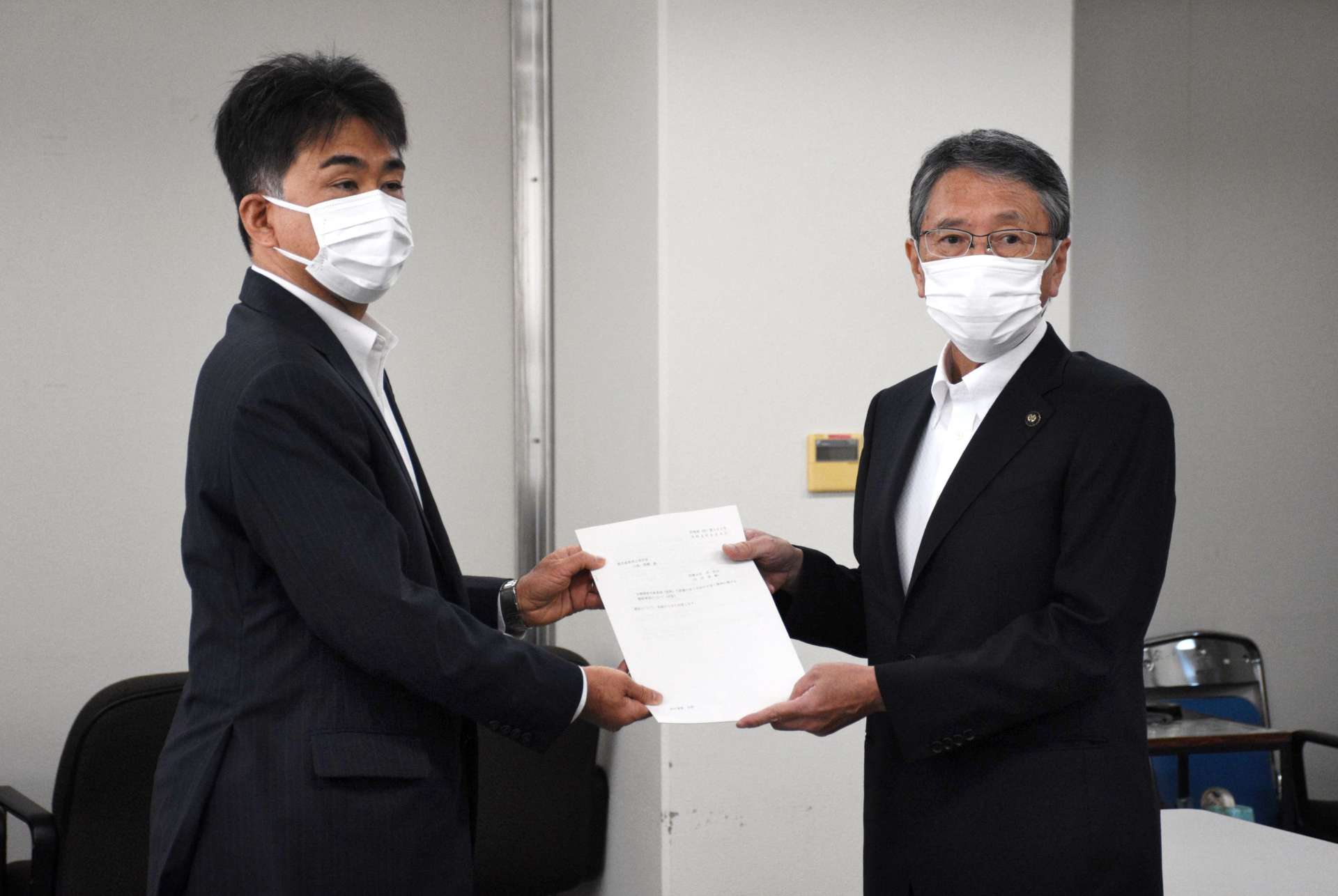 防衛省地方協力局の田中利則次長（左）から回答書を受け取る西之表市の八板俊輔市長＝同市役所