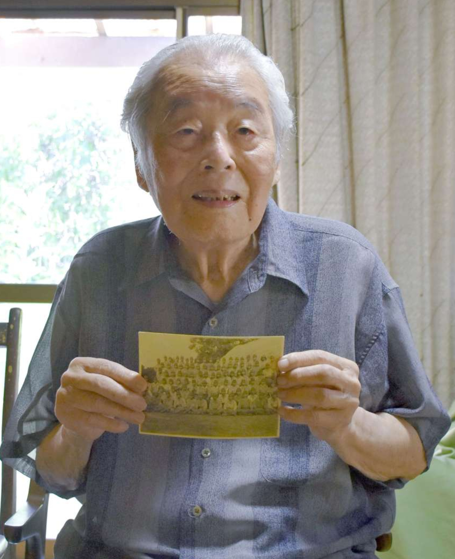 「平和であることに越したことはない」と語る川村正道さん。手にするのは兵舎の前で除隊間際に撮った戦車特攻隊員の記念写真
