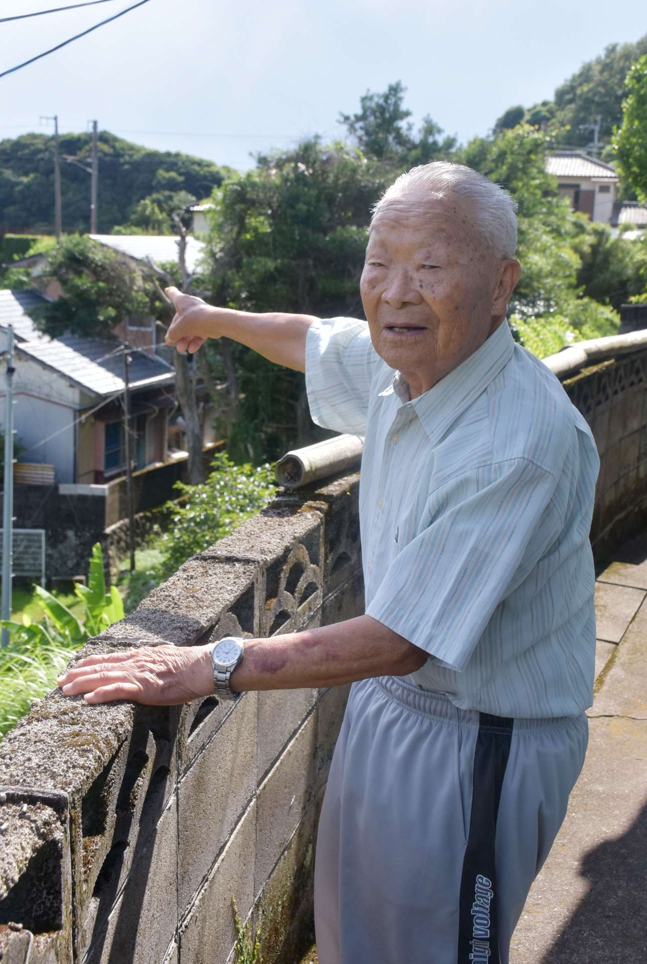 空襲警報のサイレンが設置されていた方角を示す寺地輝男さん＝阿久根市大川