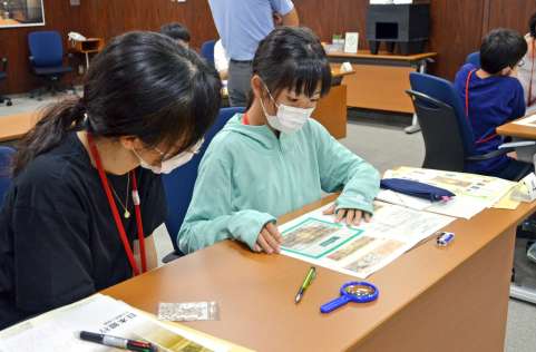 破れたり燃えたりしたお札の面積を確認する作業を体験する親子＝鹿児島市の日銀鹿児島支店