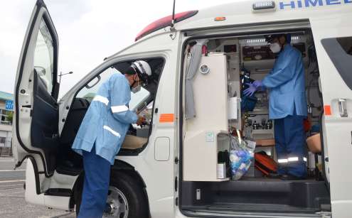 感染防止衣を身にまとい、救急車に乗り込む救急隊員＝１７日午後、鹿児島市天保山町の鹿児島市消防局中央消防署中央本署