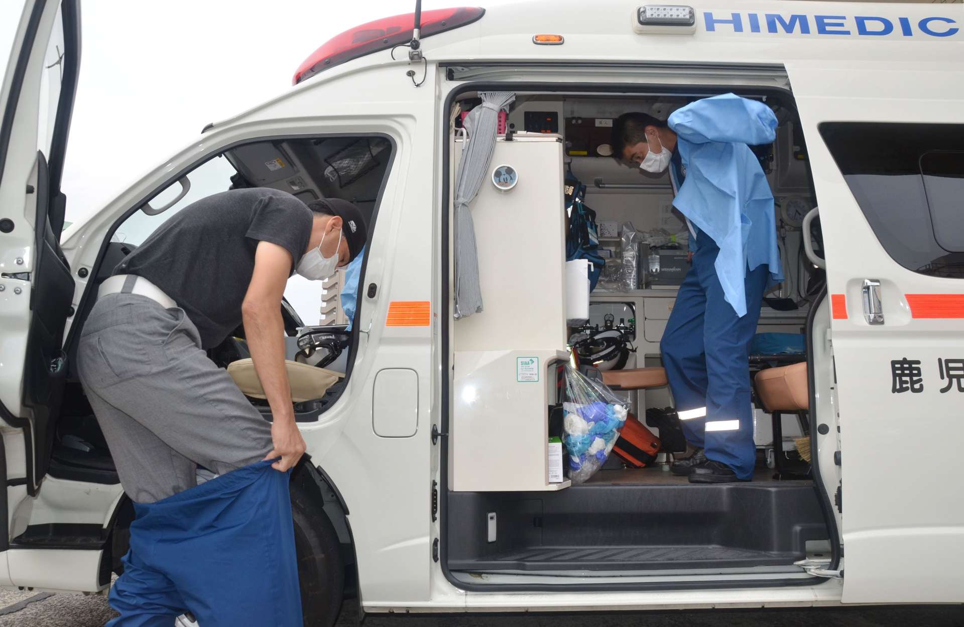 感染防止衣や手袋を素早く身につけ、救急車に乗り込む救急隊員＝１７日午後、鹿児島市天保山町の鹿児島市消防局中央消防署中央本署