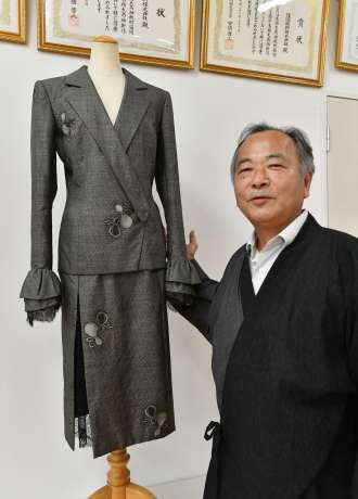 森英恵さんがデザインした大島紬のスーツを紹介する窪田政幸社長＝１８日、鹿児島市東開町