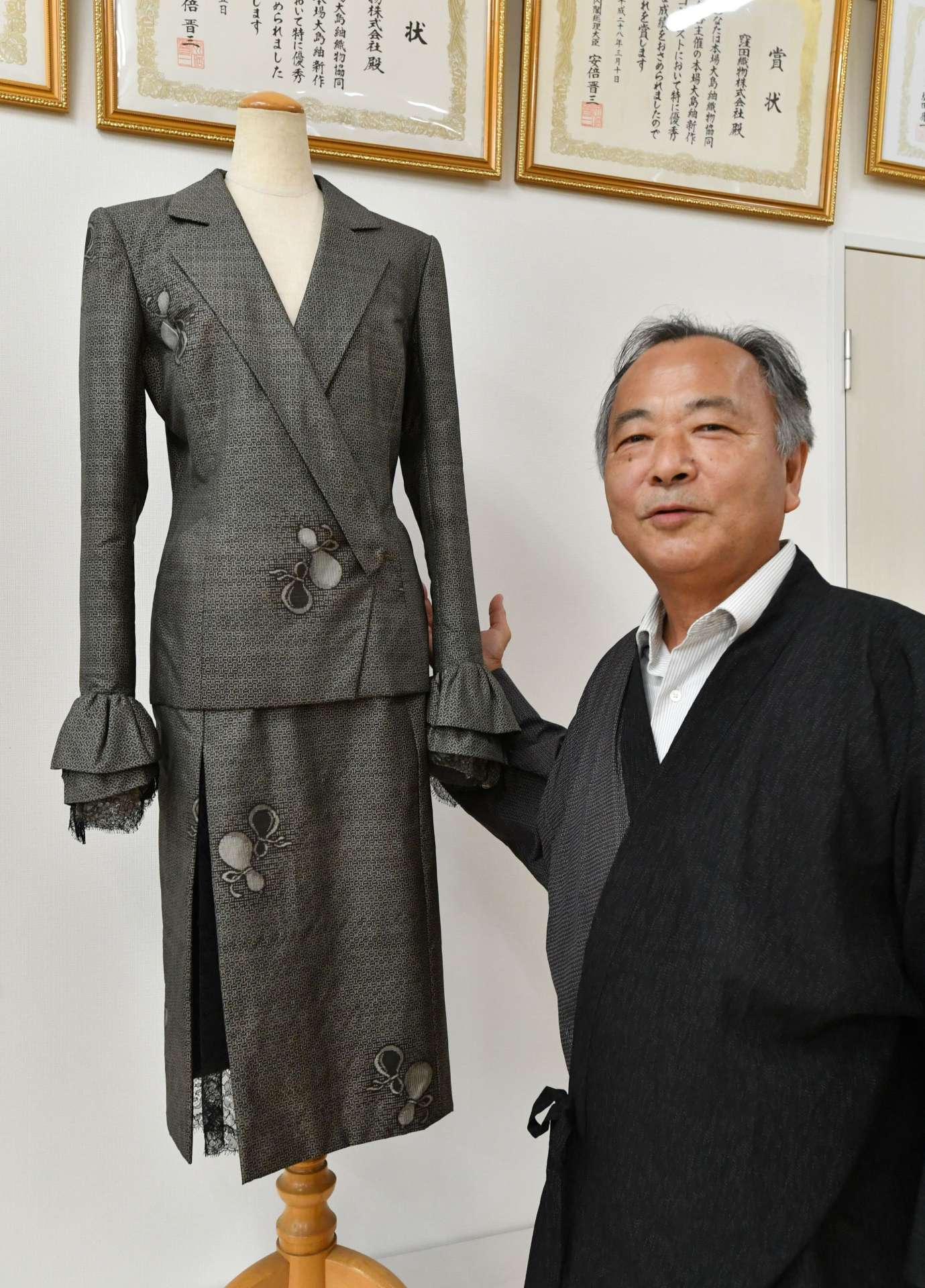 森英恵さんがデザインした大島紬のスーツを紹介する窪田政幸社長＝１８日、鹿児島市東開町