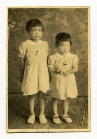 父の加治木優さんが買ってくれた姉とおそろいのワンピースを着て記念写真を撮る４歳の丸野茂子さん（右）