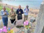 震洋隊の碑に手を合わせる住民＝１９日、南さつま市笠沙町片浦