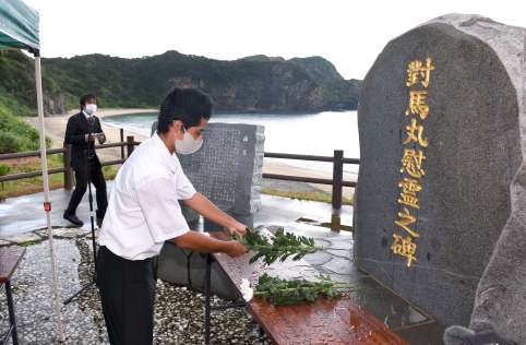 慰霊碑に花を供え、犠牲者の冥福を祈る参列者＝２７日、宇検村宇検