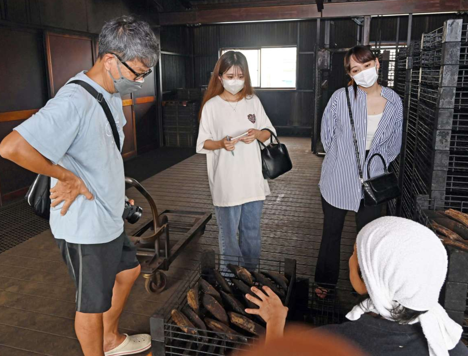 かつお節づくりの工程の説明に聞き入る安武はなさん（左から２人目）＝枕崎市桜木町