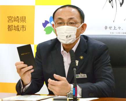 稲盛イズムをベースに作製した「都城フィロソフィ手帳」を胸から取り出す池田宜永市長＝都城市役所
