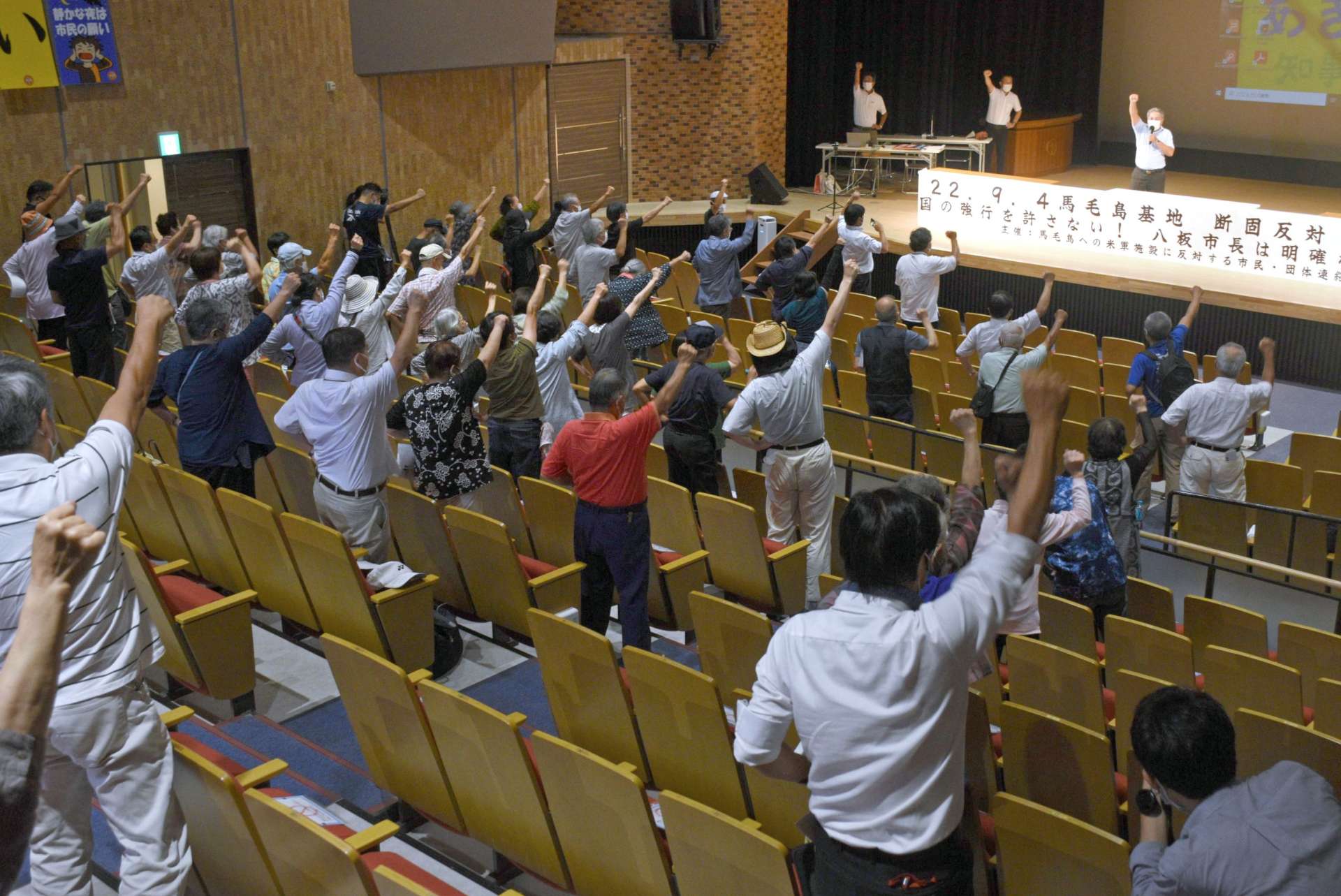 「基地反対」の気勢を上げる参加者＝西之表市民会館