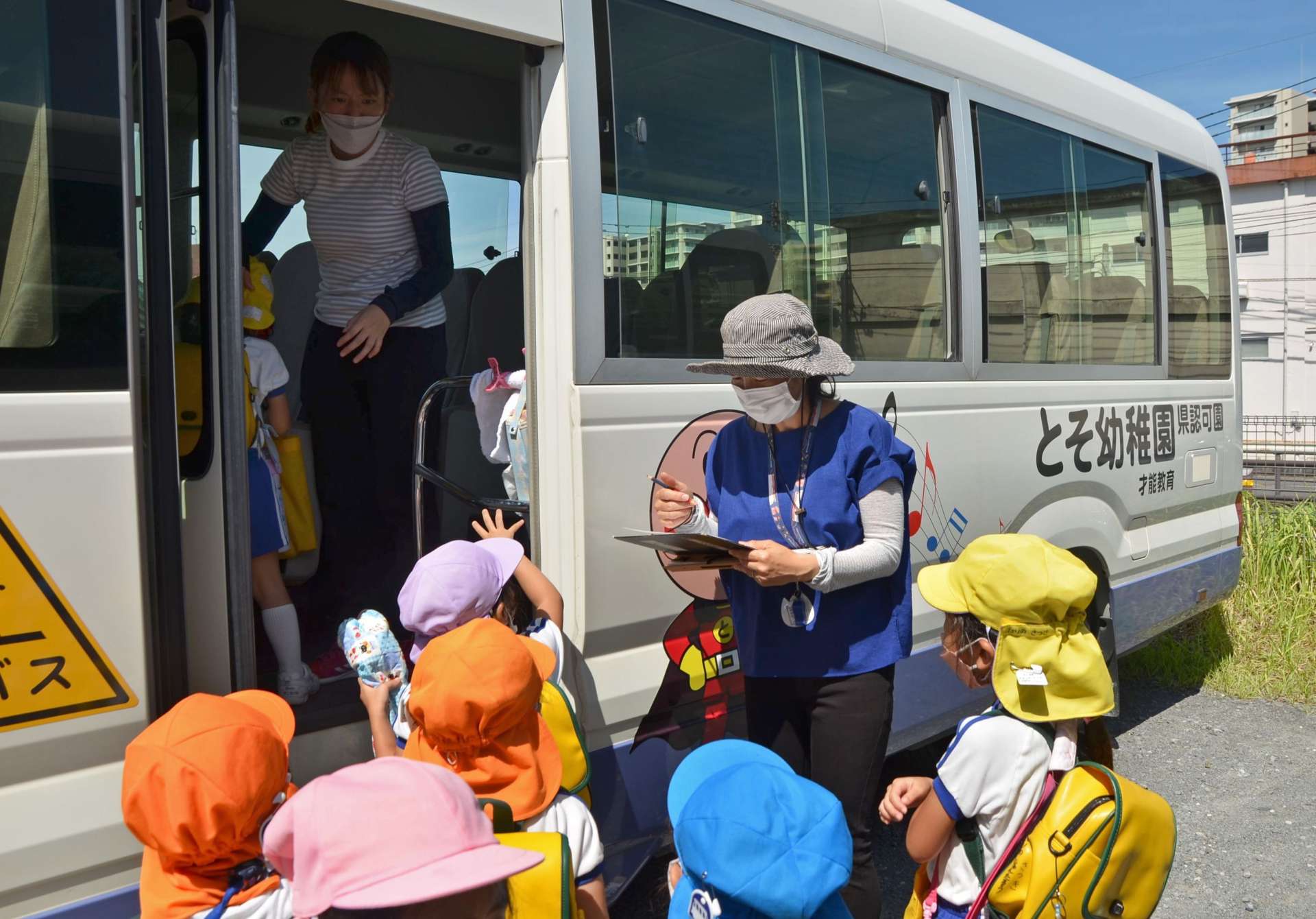 帰宅のため乗車する園児を確認する教諭＝７日午後、鹿児島市唐湊４丁目