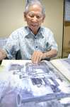 米進駐軍が上陸して自宅近くを通る様子を捉えた写真を見る立元良三さん＝鹿屋市高須町