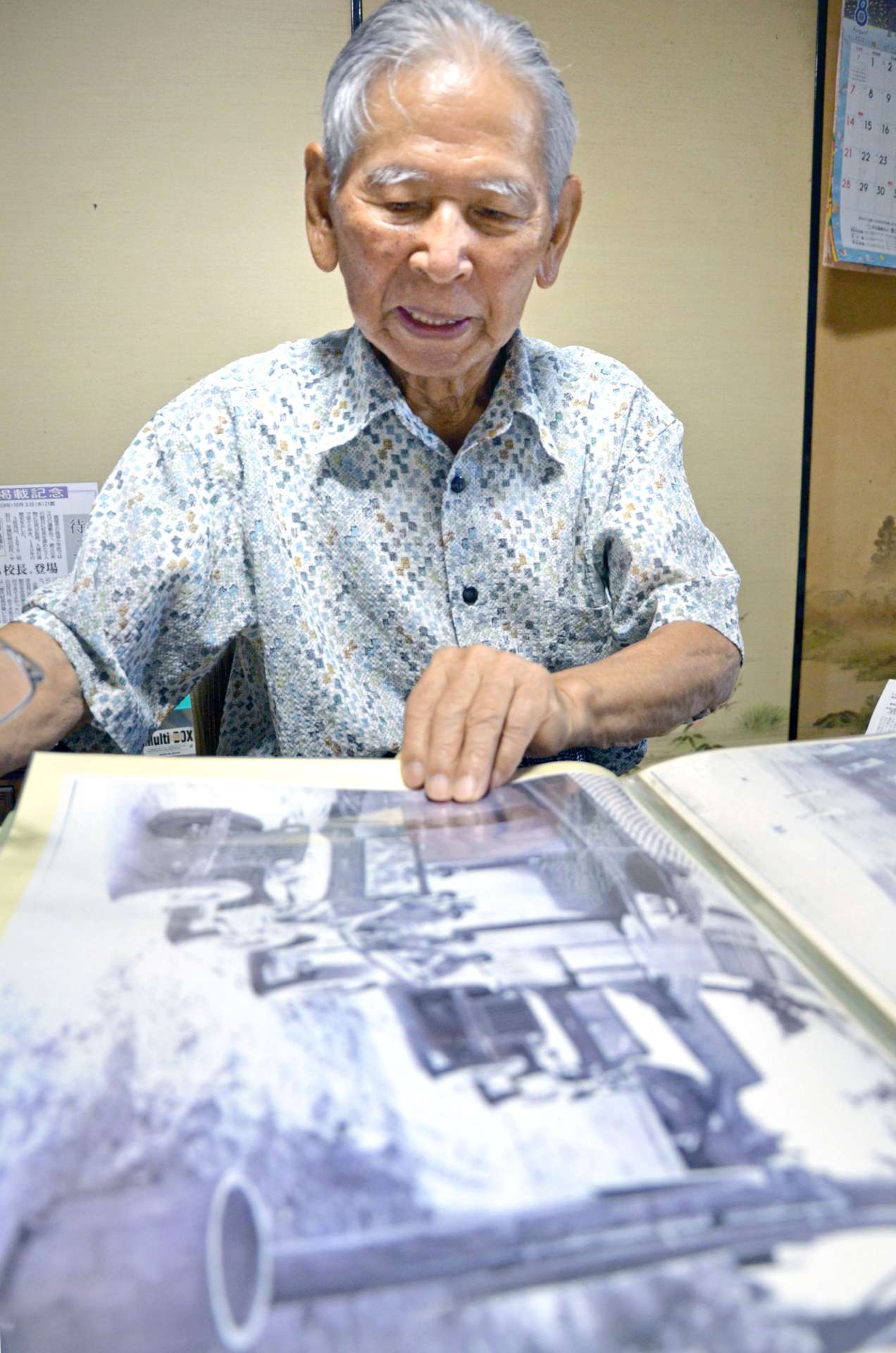 米進駐軍が上陸して自宅近くを通る様子を捉えた写真を見る立元良三さん＝鹿屋市高須町