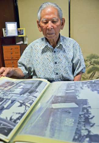 米進駐軍が鹿屋に上陸する様子を捉えた写真を見る立元良三さん＝鹿屋市高須町