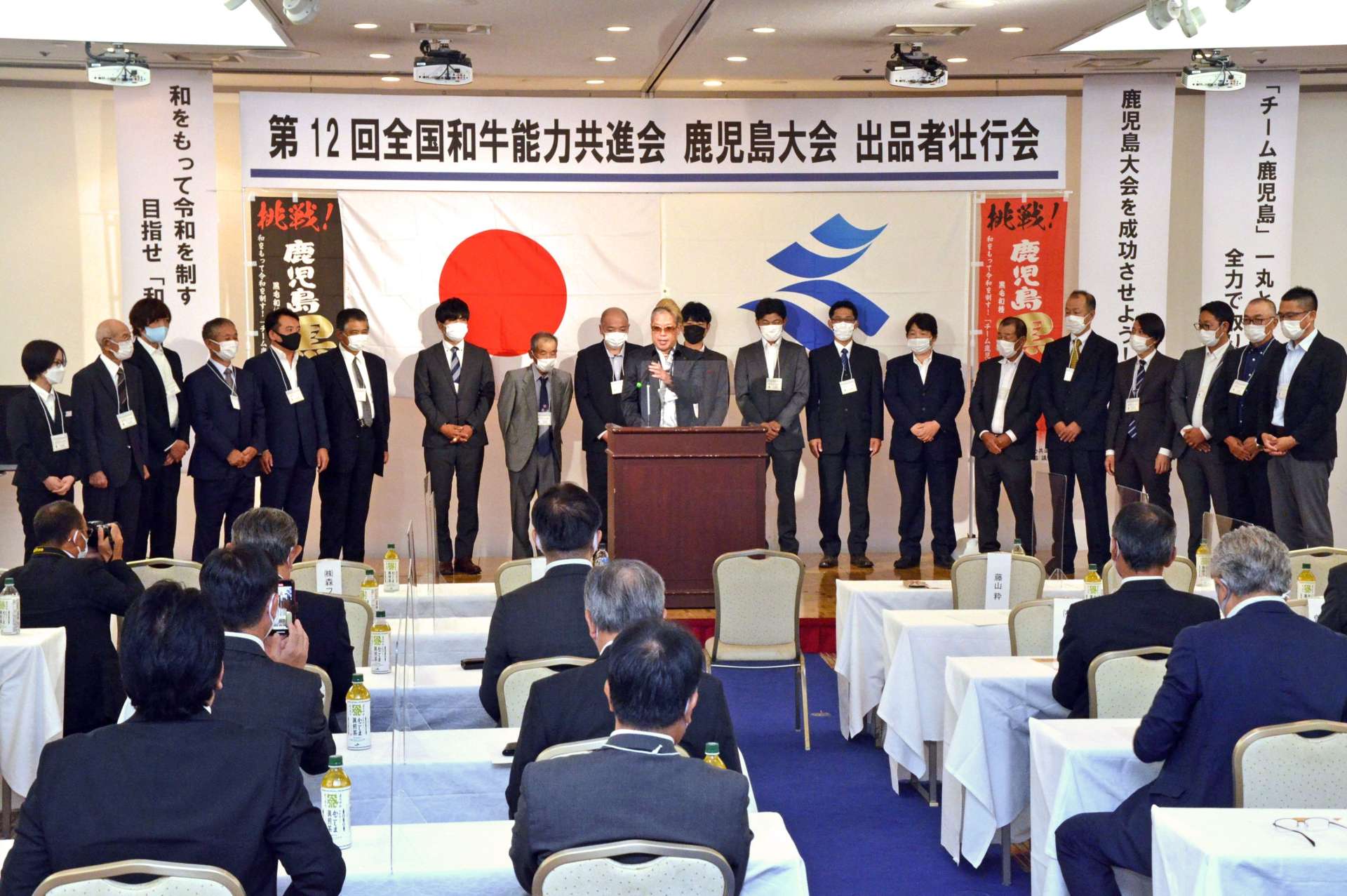 壇上に並ぶ出品者を代表し、決意表明する藤山粋さん（中央）＝鹿児島市のアートホテル鹿児島