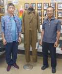 寄贈された飛行服。左近充清典さん（左）と岩川芙蓉会の持田初穂会長＝曽於市大隅町月野の市埋蔵文化財センター