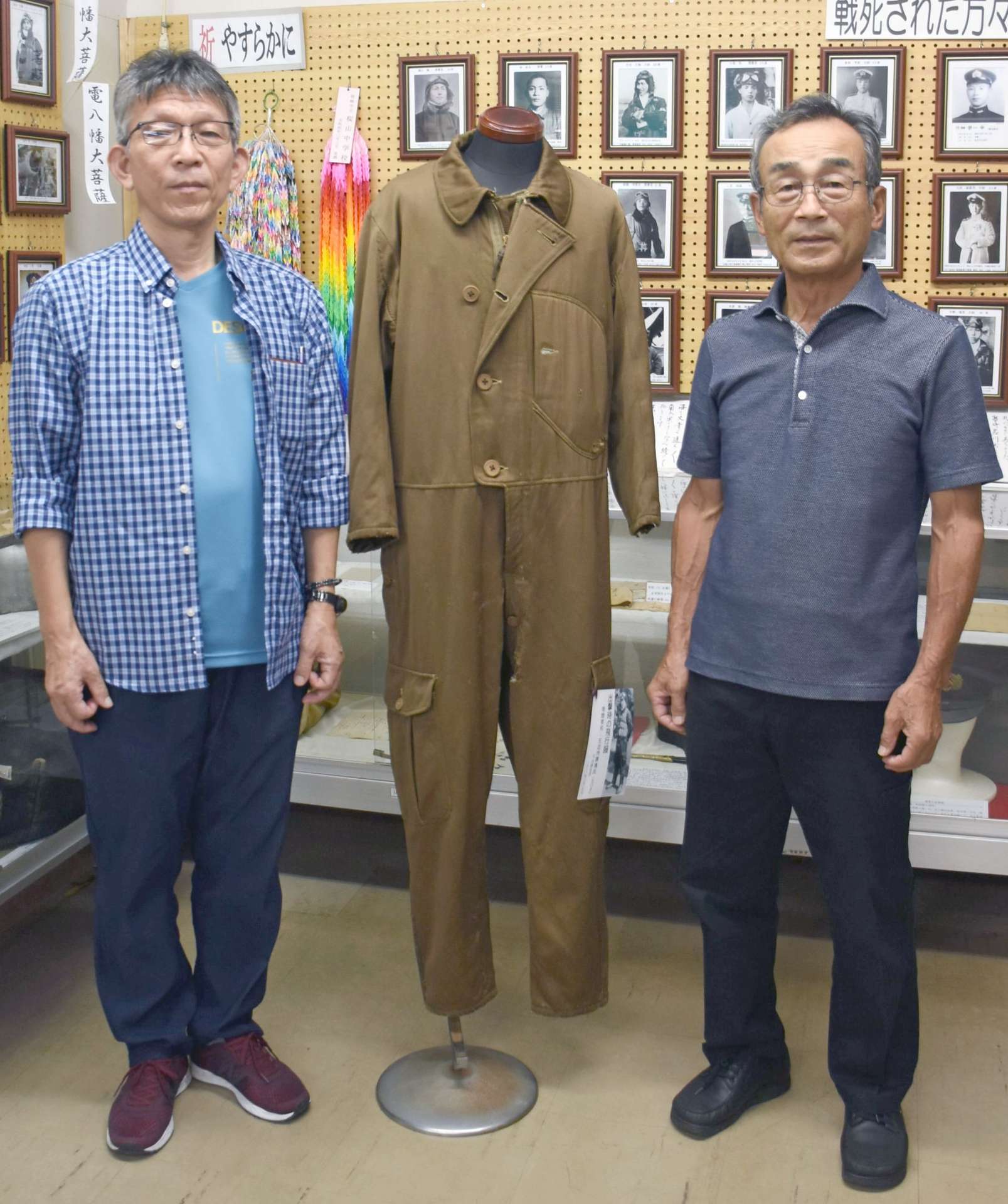 寄贈された飛行服。左近充清典さん（左）と岩川芙蓉会の持田初穂会長＝曽於市大隅町月野の市埋蔵文化財センター
